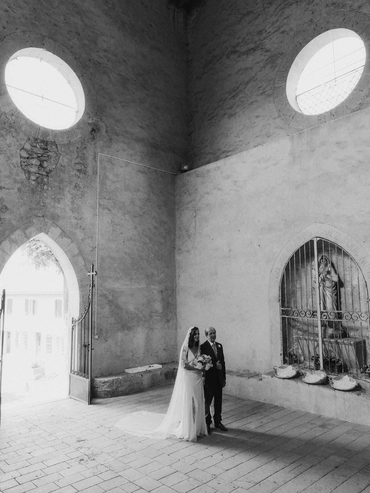 bride and father standing inside an old church in pessan france