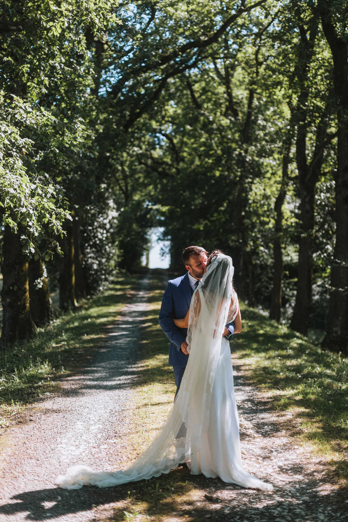 bride and groom posing in a forest on the grounds of chateau de lartigolle