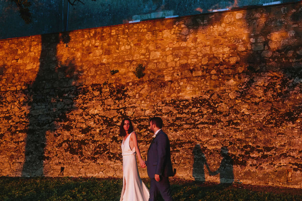 wedding couple photographed against a brick wall at chateau de lartigolle during sunset