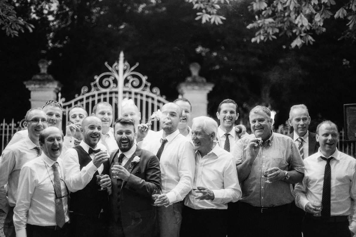 documentary style photo of a group of men at a wedding smoking cigars