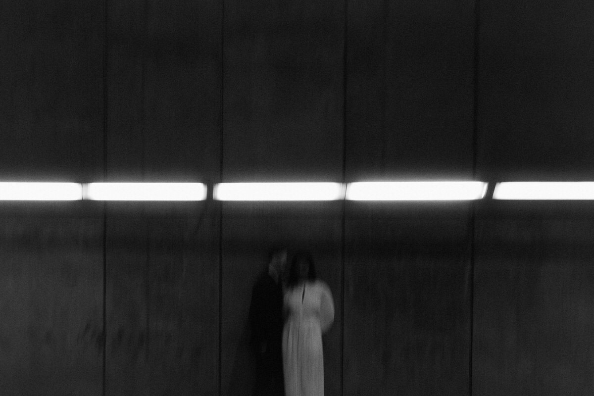 cinematic style photo of bride and groom standing below a single light source