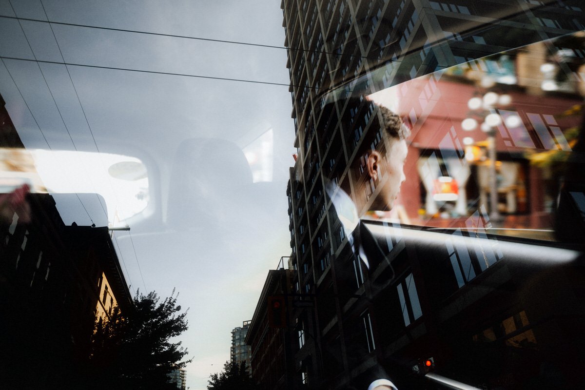 abstract reflection photo of groom sitting inside a taxi