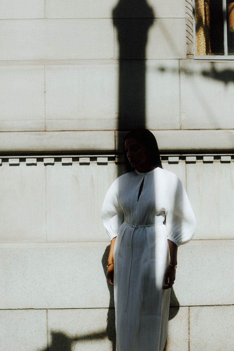 bride standing in the shadow of a lamp post while wearing issey miyake pleated dress