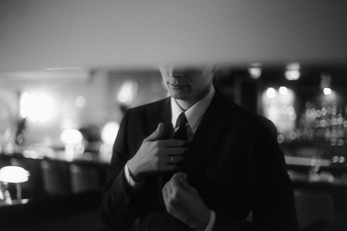 groom fixing his tie in front of a mirror inside kissa tanto