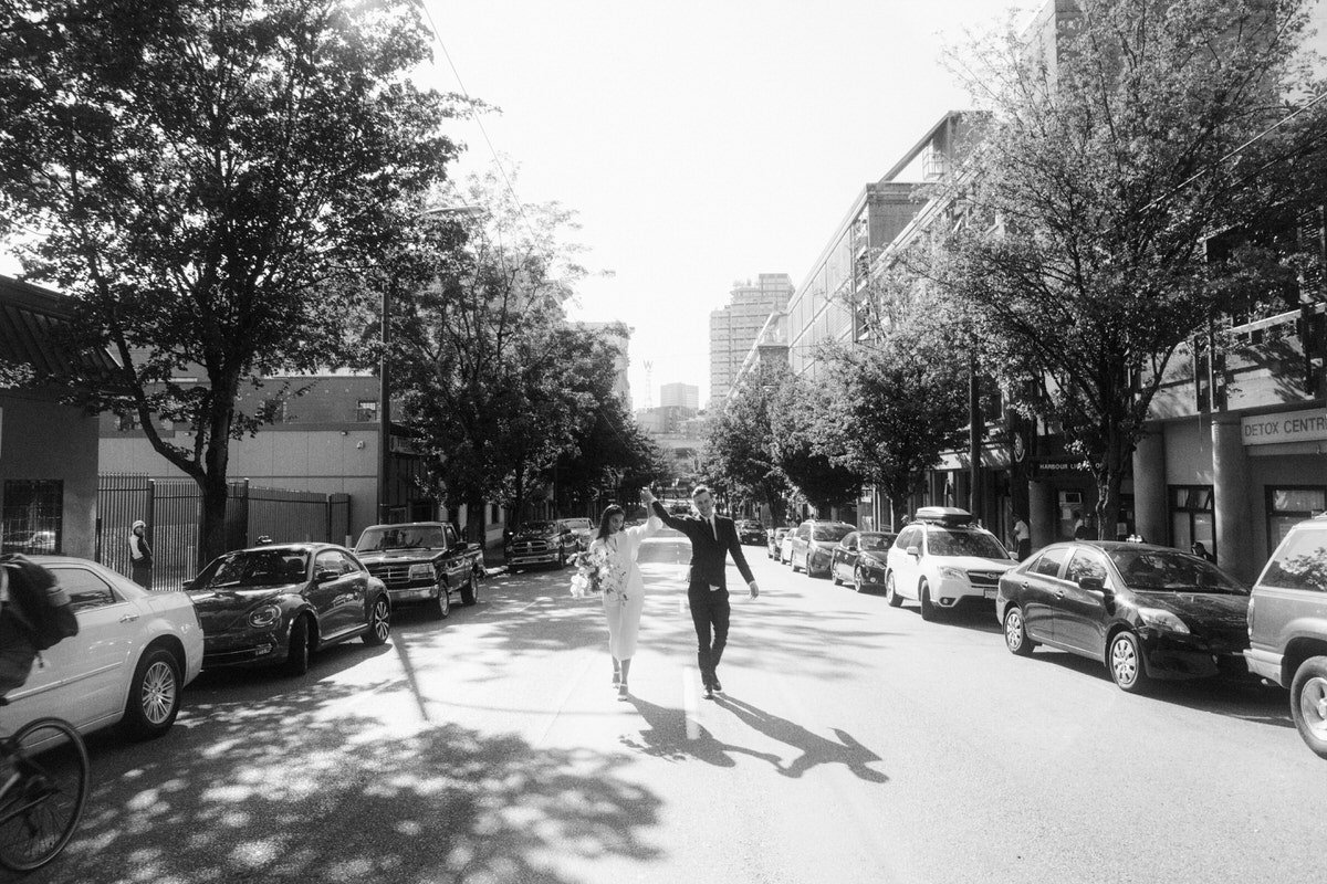 bride and groom walking down the centre of a street in downtown vancouver
