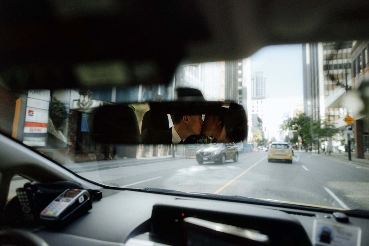 reflection of bride and groom kissing inside a taxi in vancouver