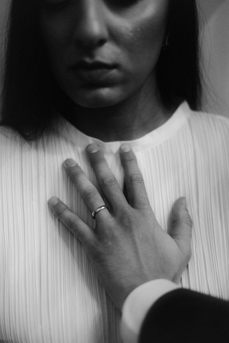 groom holding his hand over the brides heart while displaying his wedding ring