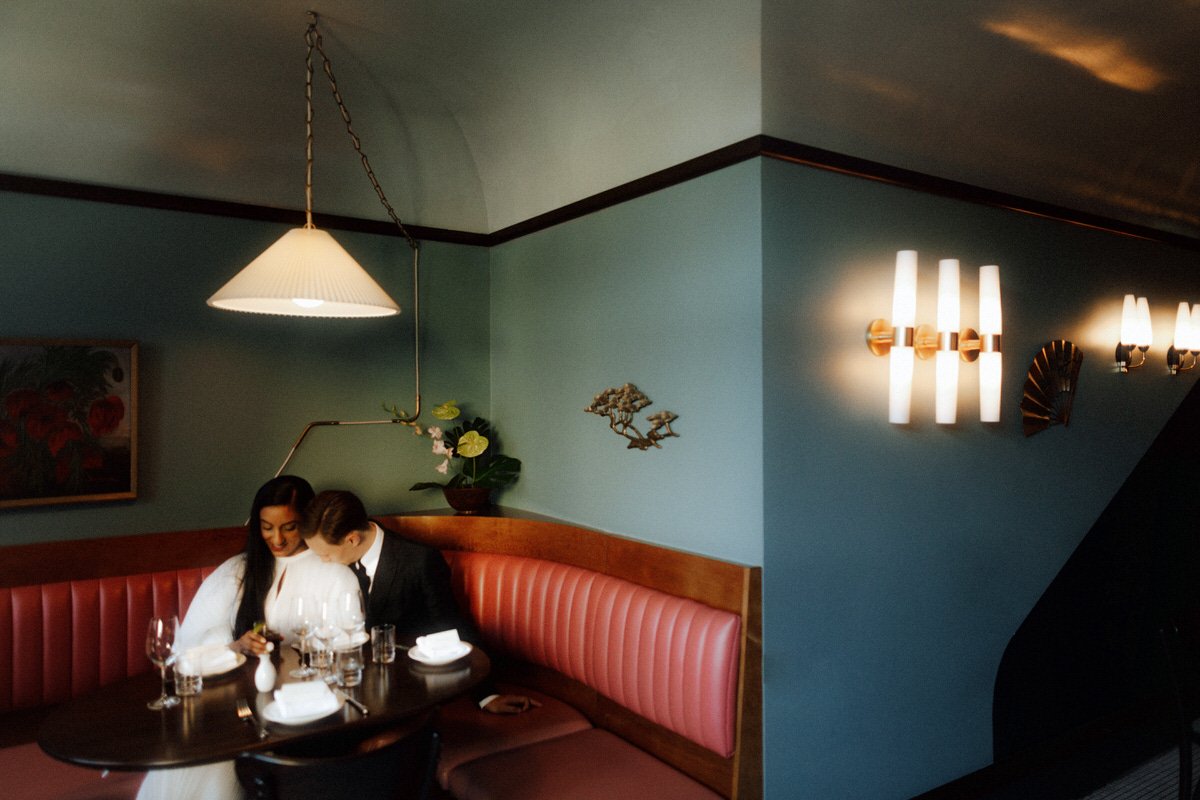 bride and groom sitting in a booth inside kissa tanto in vancouver
