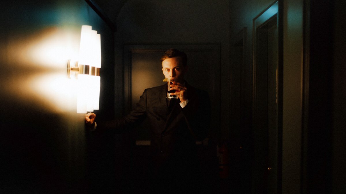 man holding a drink and lit by aesthetic lighting inside a restaurant