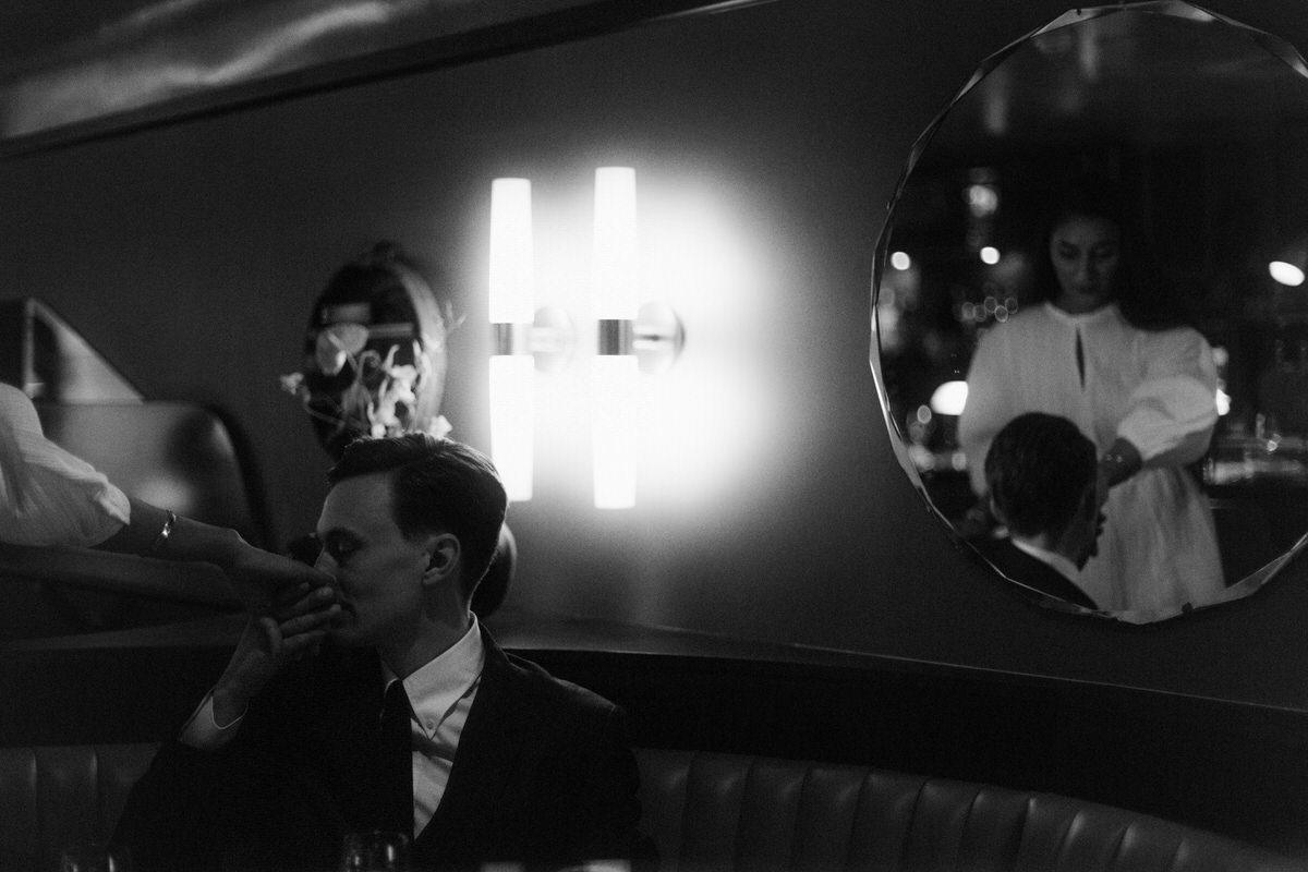groom kissing brides hand while she is reflected in a mirror inside an aesthetic restaurant