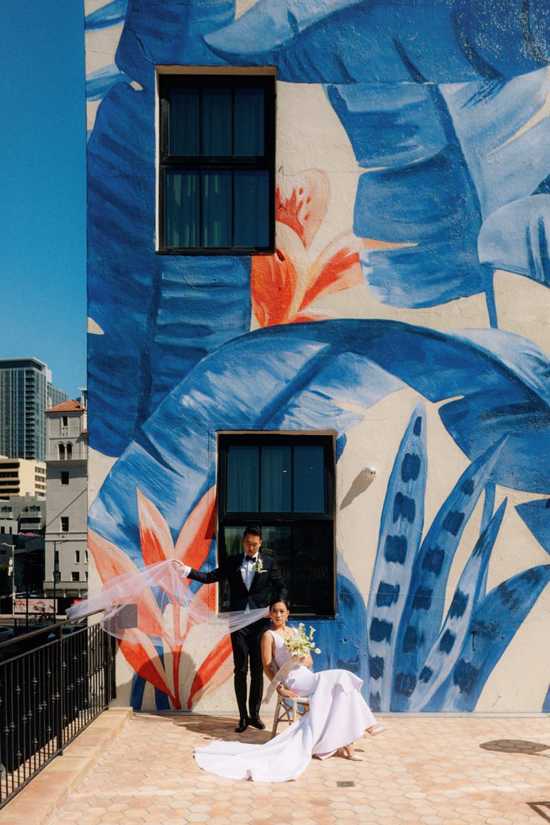 wedding couple posing in front of Bella Gomez mural at Hotel Figueroa LA