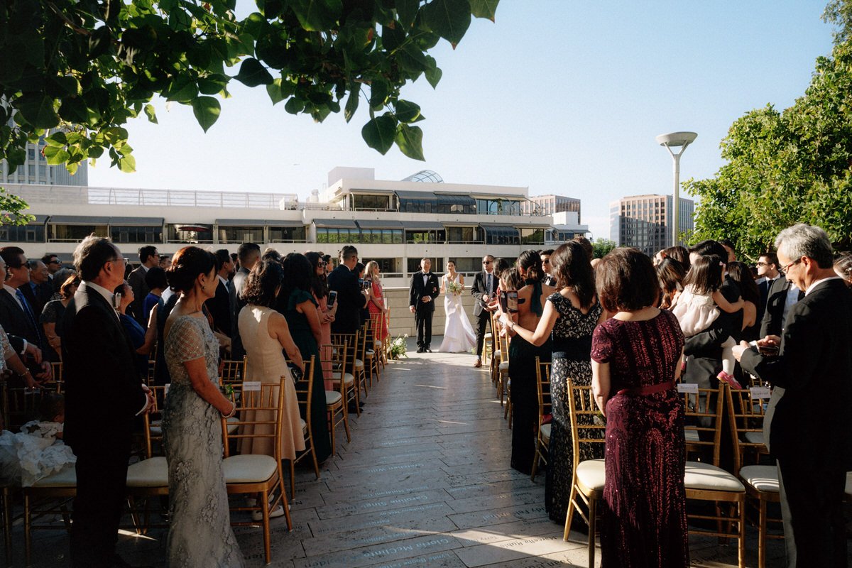 bride and her father entering the ceremony while wedding guests look on in downtown LA