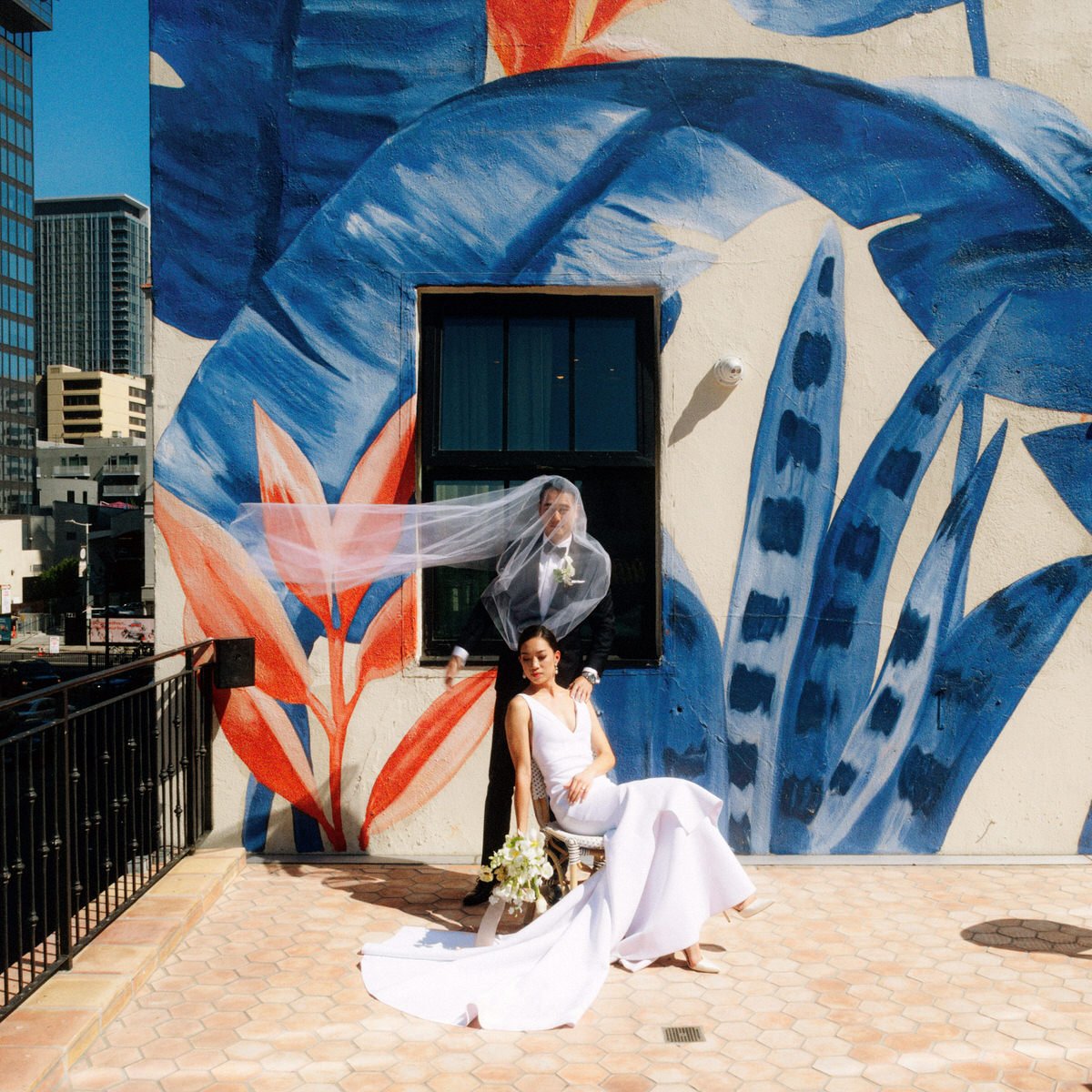 wedding couple posing in front of bella gomez mural at hotel figueroa in los angeles