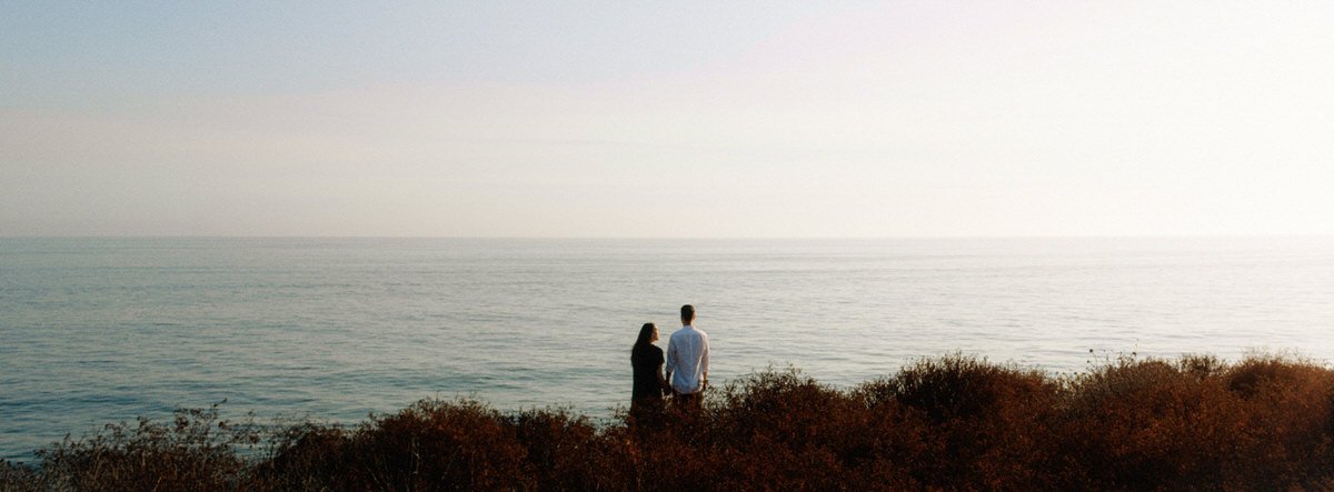 woman and man photographed amongst the grasses at Huntington State Beach during sunset