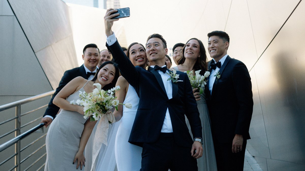 groom takes a selfie photo with the entire wedding party at Walt Disney Concert Hall