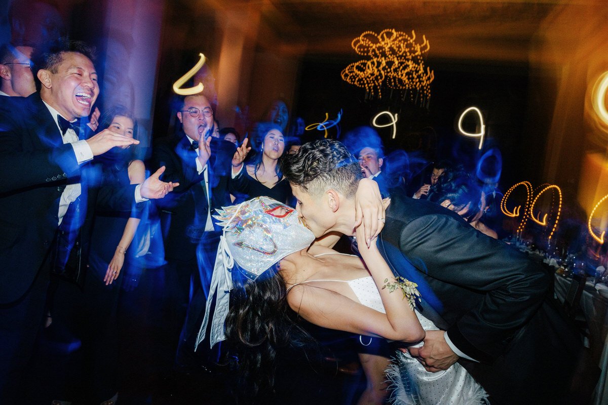 fun capture of groom kissing his bride wearing a luchador mask
