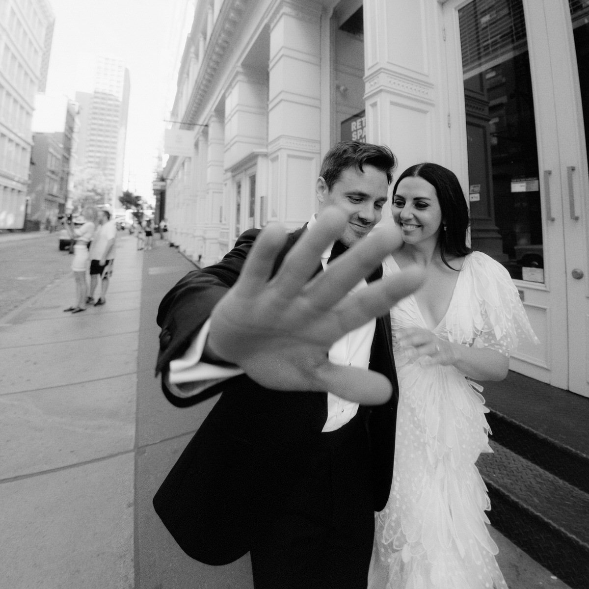 editorial style photo of groom holding out hand towards paparazzi style photographer