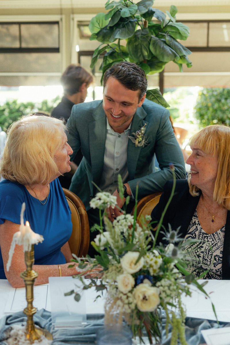 groom happily chatting with wedding guests during dinner reception at Teahouse in Stanley Park