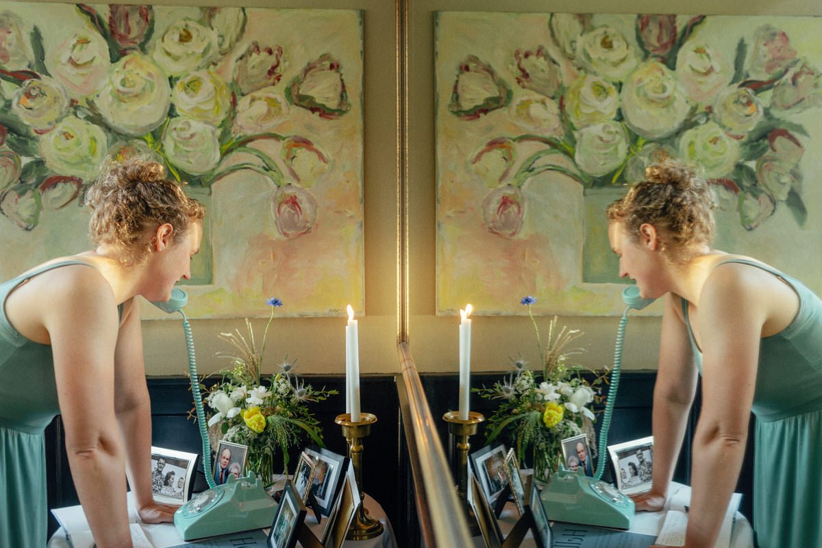 reflection photo of wedding guest using vintage rotary phone at a welcome table
