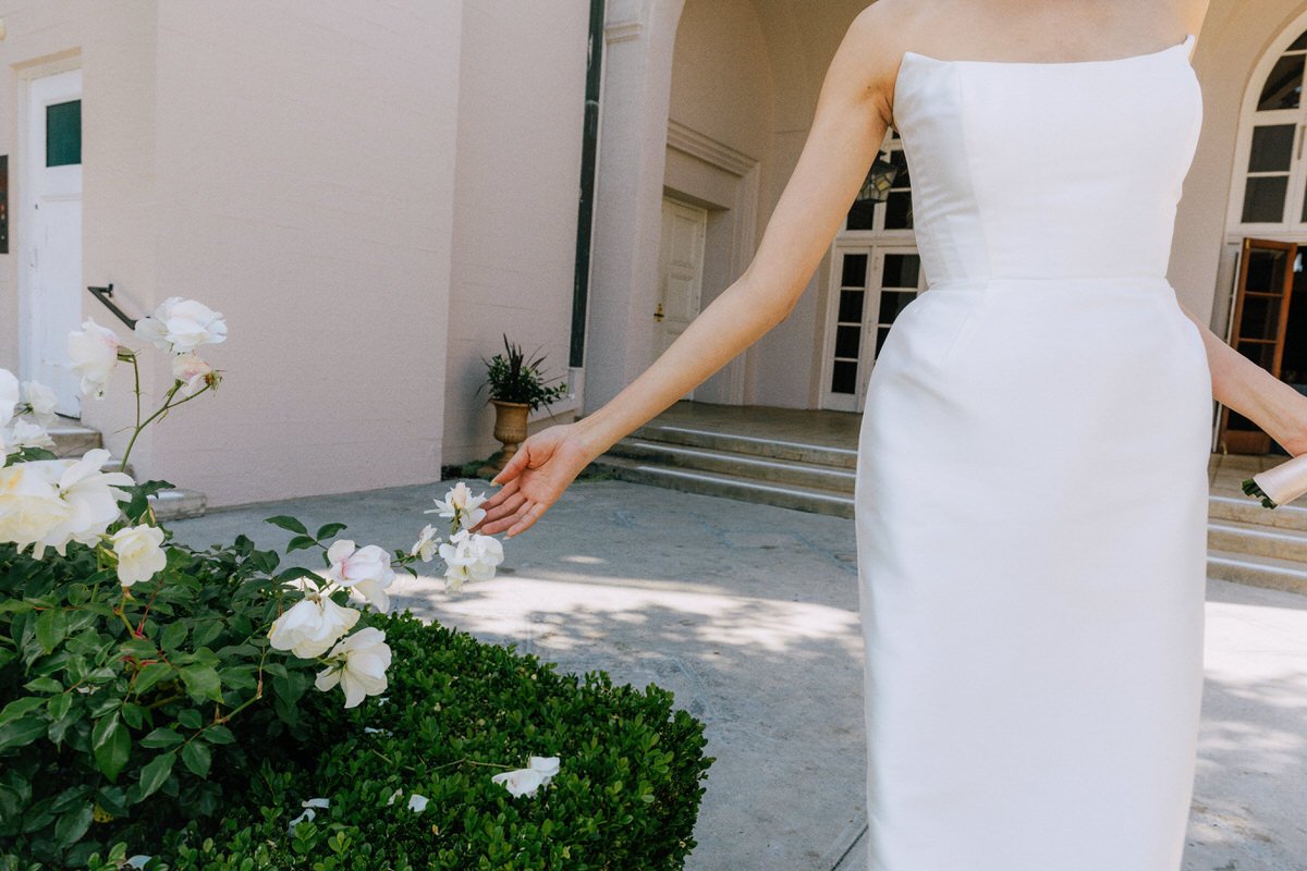 bride touching the white roses growing inside the Ebell of LA courtyard