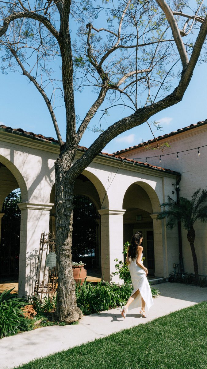 bride walking along a concrete path at midday inside the Ebell of LA