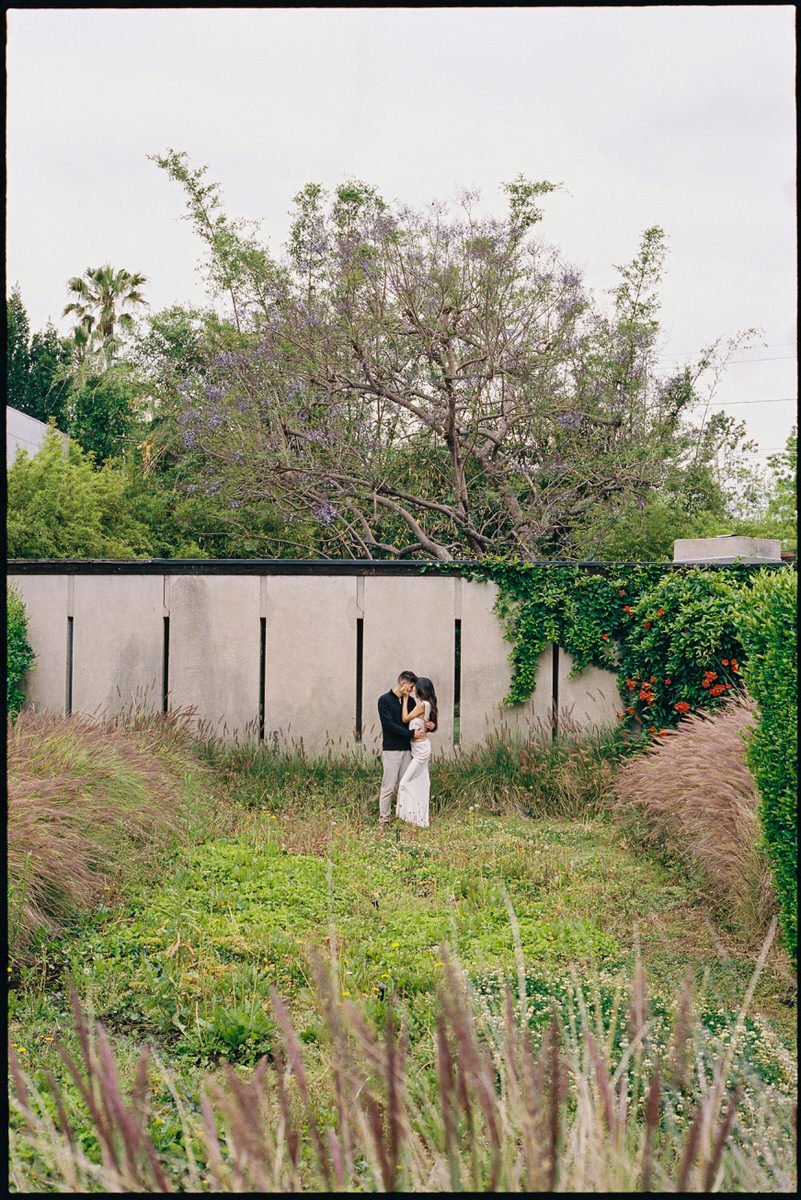 35mm film photo of engaged couple standing in a green location at Schindler House