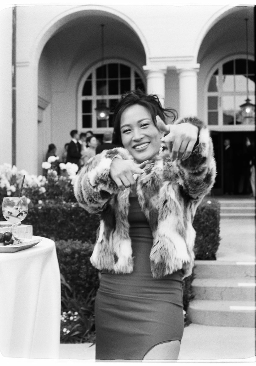 35mm film photo of stylish wedding guest wearing a fur coat and body con dress