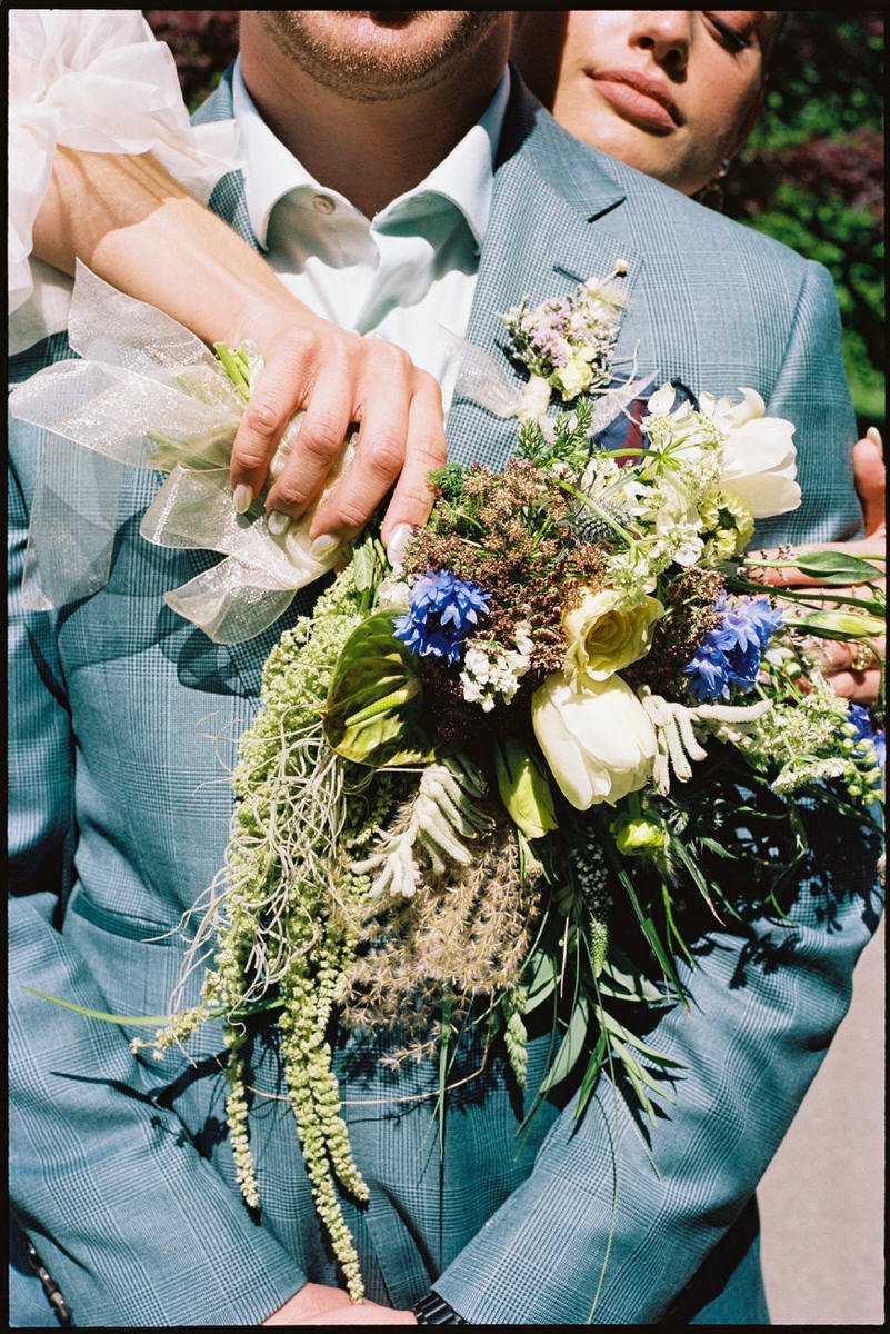 35mm film photo of wedding couple embracing while holding seasonal wildflowers bouquet in Vancouver