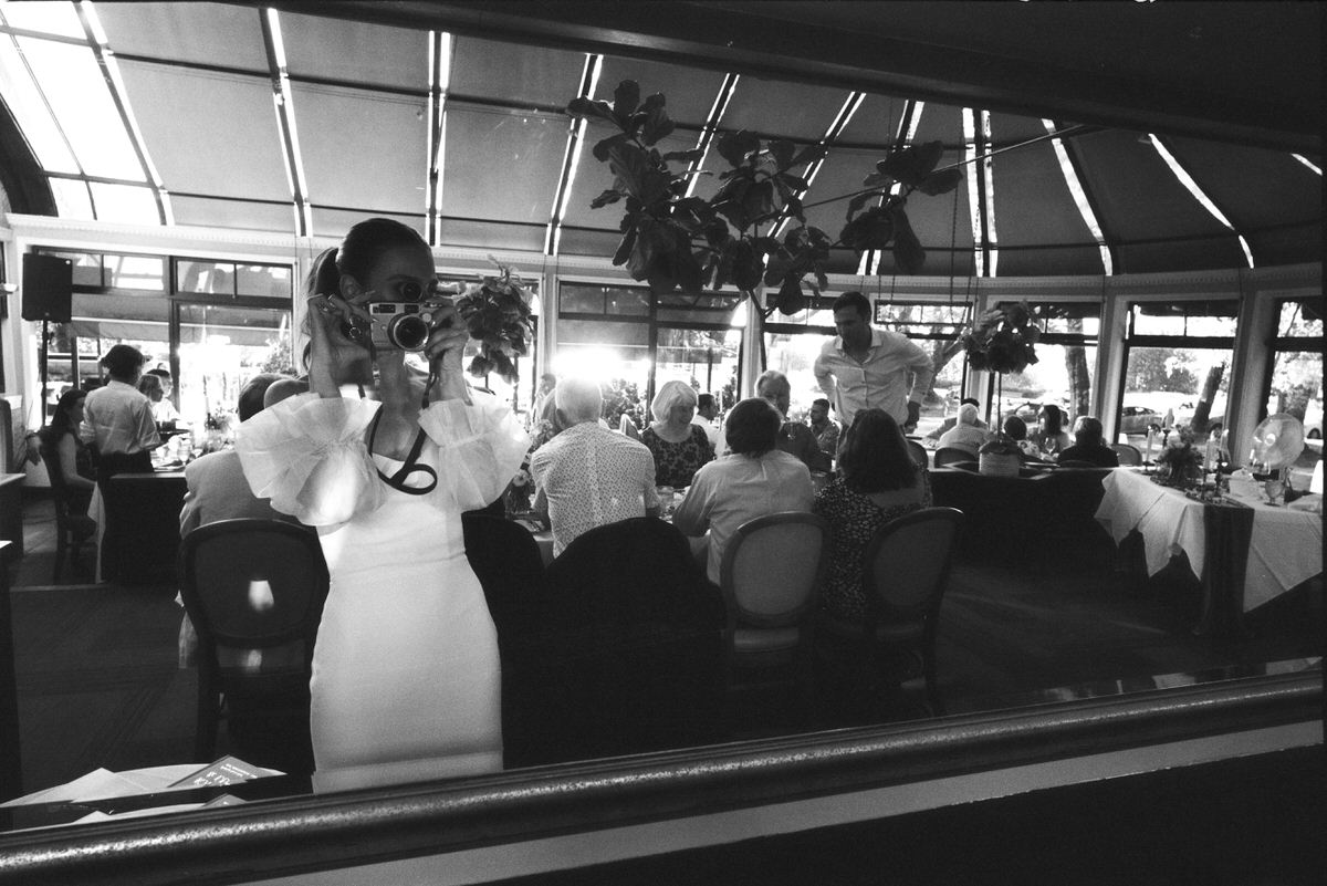 35mm film photo of bride holding a Contax G2 camera while standing in a mirror