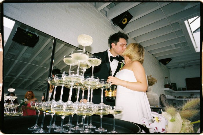35mm film photo of wedding couple kissing with champagne tower