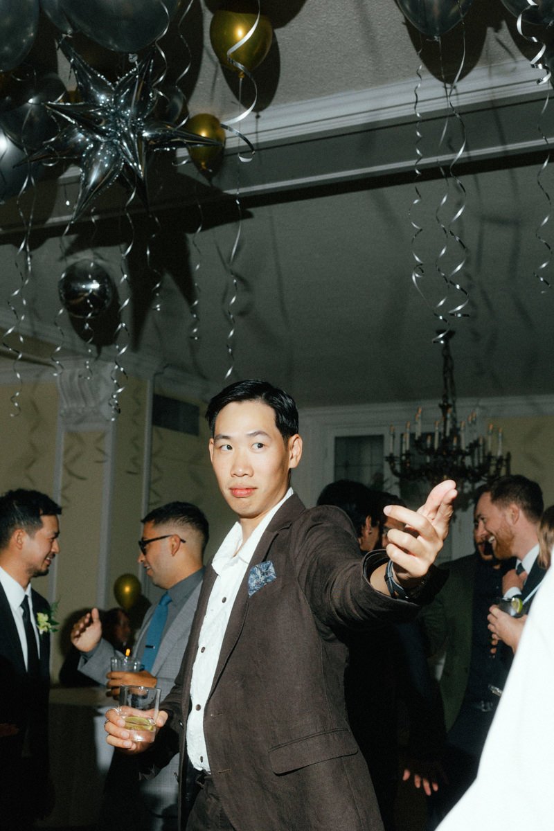 wedding guest standing under silver and gold balloons