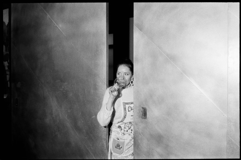 35mm film photo of bride drinking from a wine glass while standing between two sliding doors