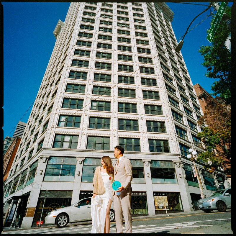 120mm film medium format photo of wedding couple standing in front of tall architecture in downtown Seattle