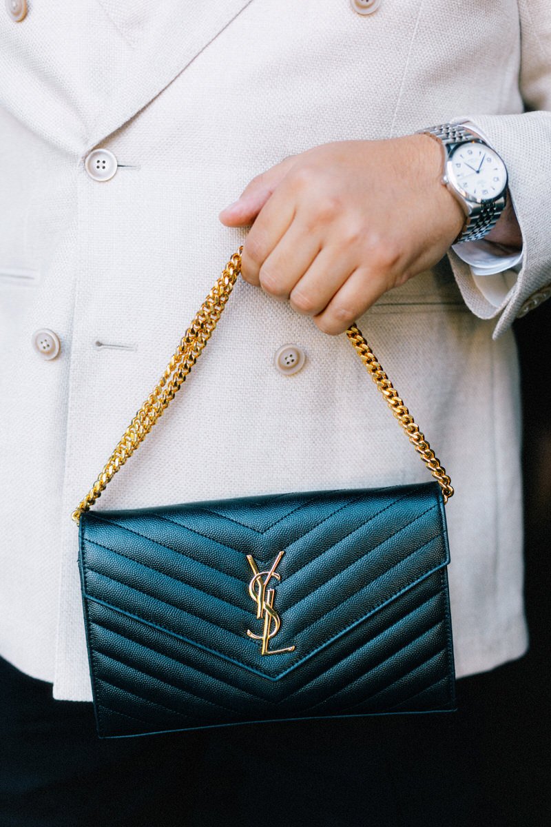 stylish wedding guest holding a Yves Saint Laurent leather purse with gold chain handle