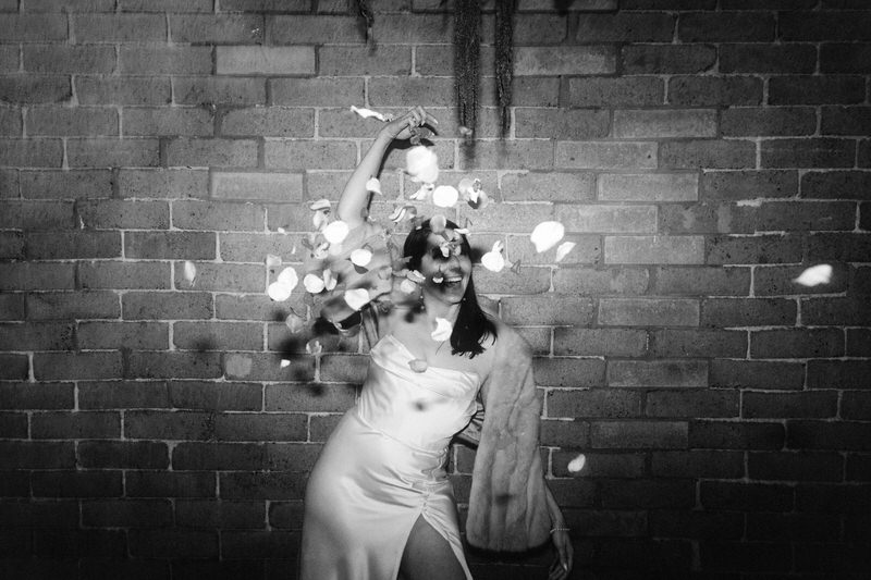 happy bride throwing flower petals at the camera