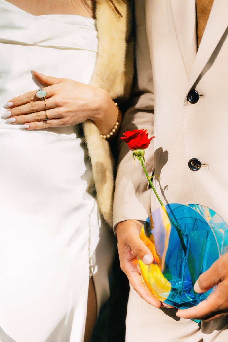bride and groom posing with an unconventional wedding bouquet using a circular vase