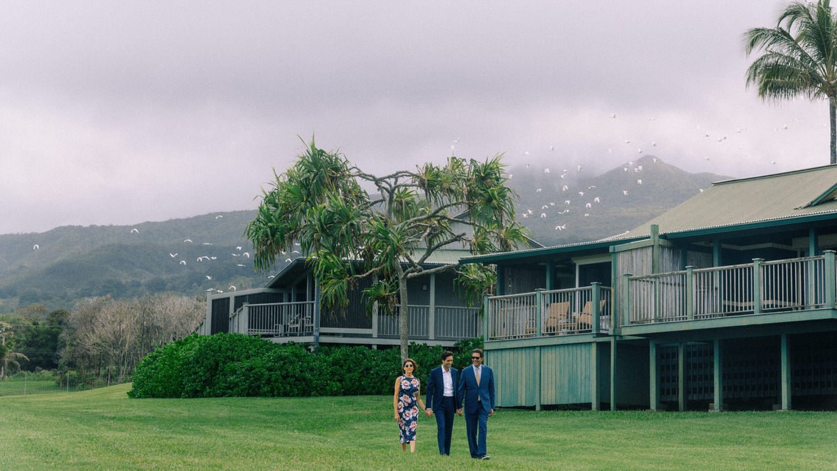 groom entering wedding ceremony with his parents as white birds fly overhead in Maui