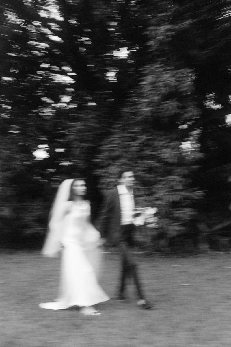 creatively blurry photo of bride and groom walking through a grove in Maui