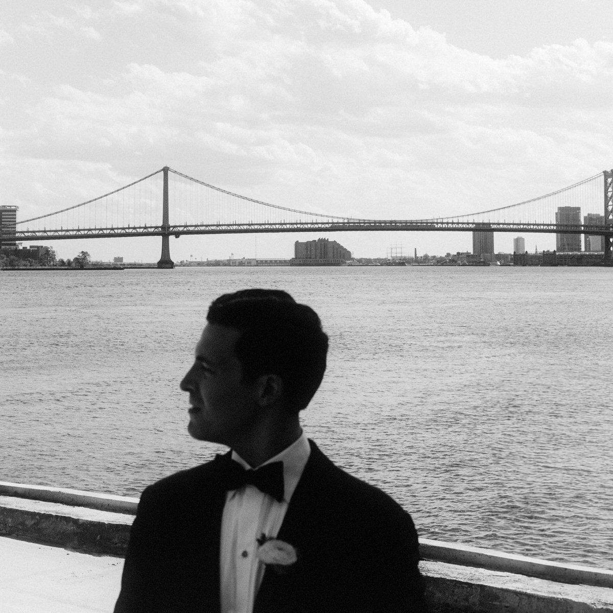 artful composition of groom with Benjamin Franklin Bridge in the background