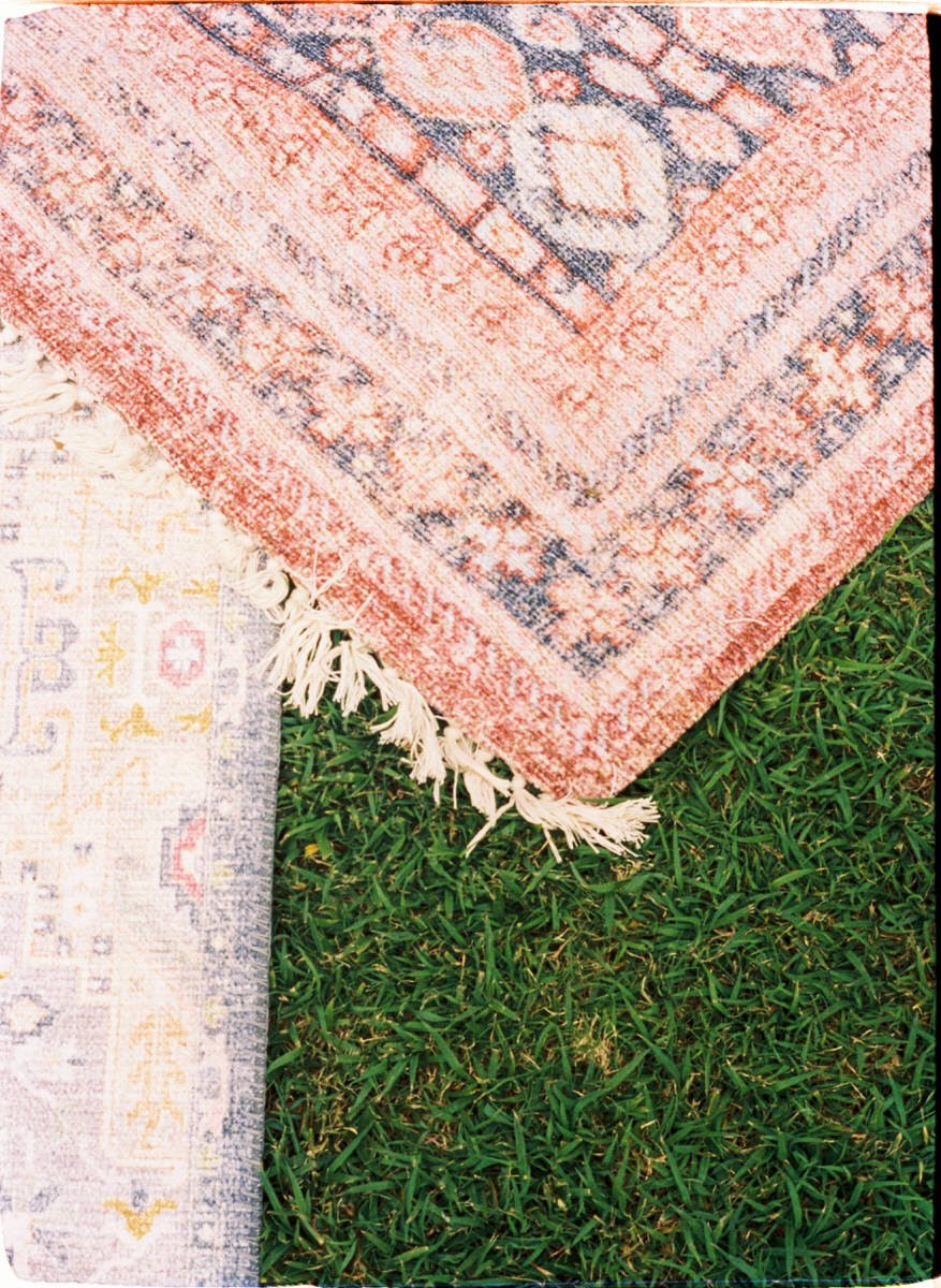 35mm film photo of boho rugs resting on top of grass at a wedding ceremony in Maui