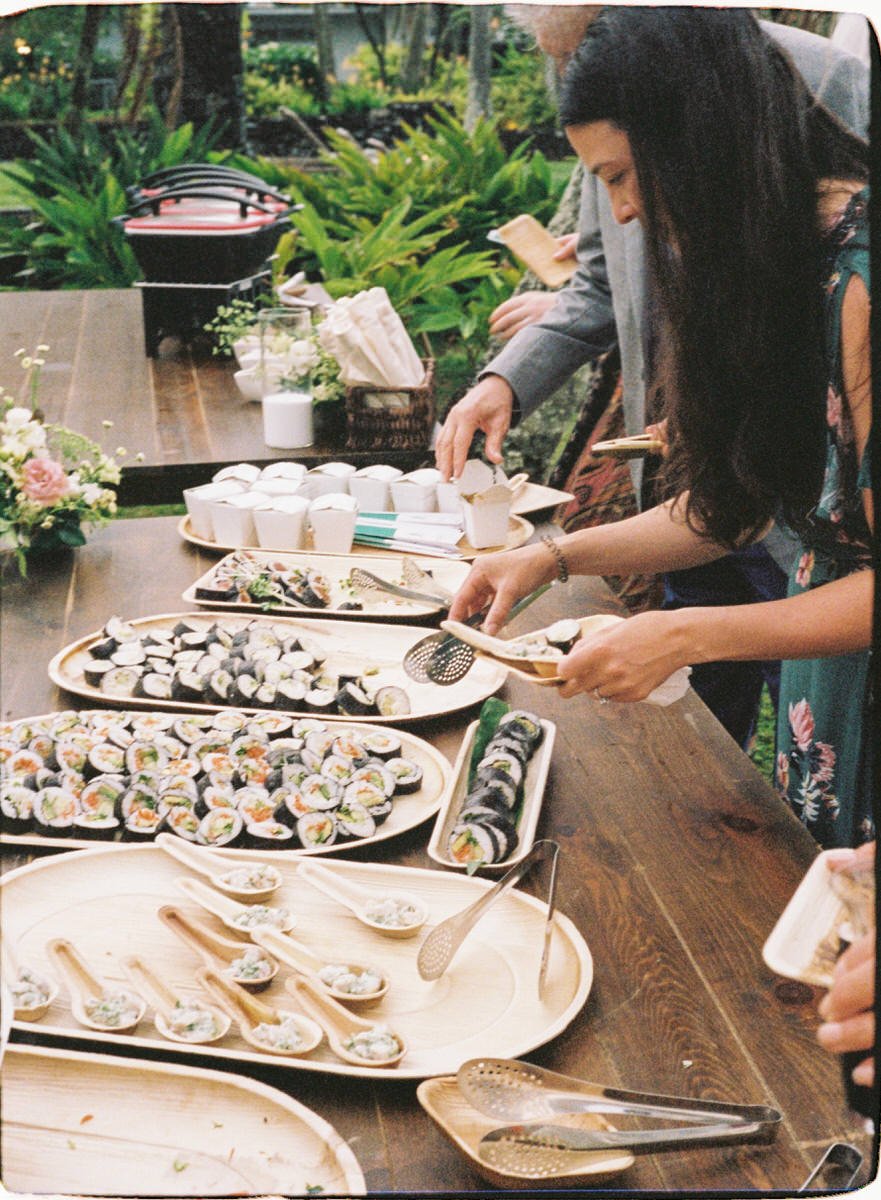 35mm film photo of wedding guests treating themselves to sushi during cocktail hour in Hawaii