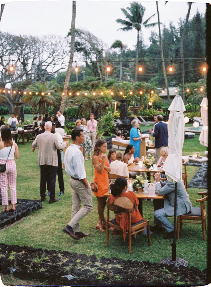 35mm film photo of guests standing below cafe lights at a beautiful wedding venue in Maui