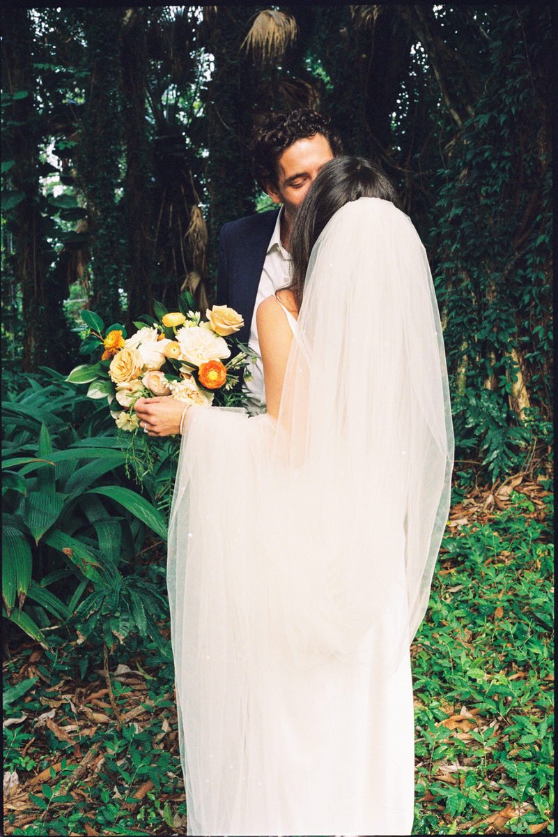 35mm film photo of bride and groom kissing under the palm trees in Hawaii