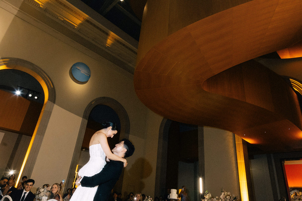 groom lifting the bride during their first dance under the Frank Gehry spiral staircase at the AGO