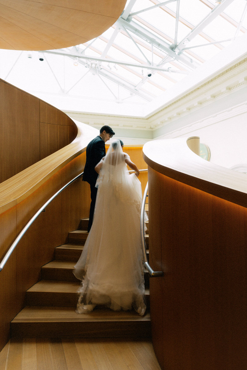 wedding couple walking up the Frank Gehry spiral staircase inside the AGO