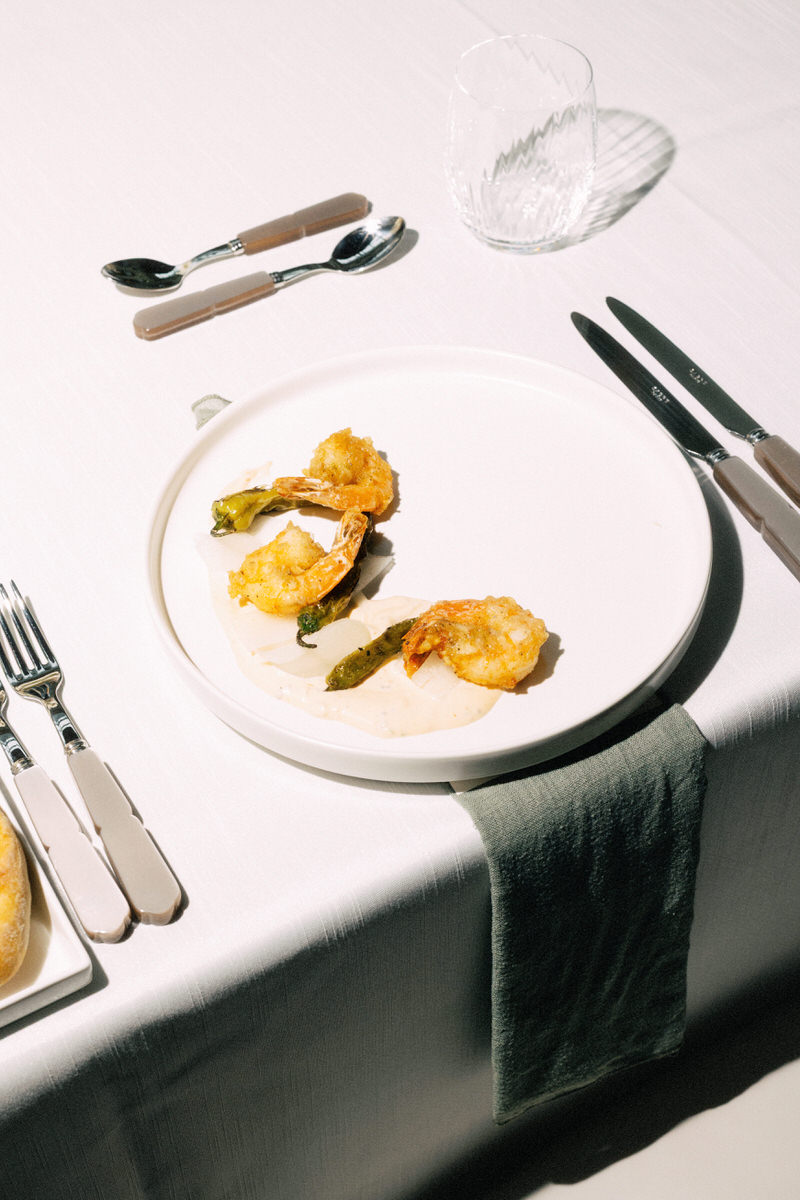 shrimp and shishito pepper appetizer course on a round white plate
