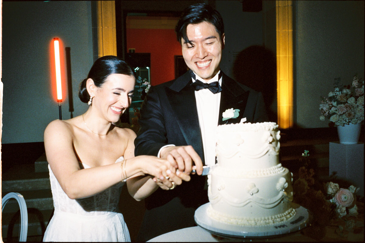 35mm film photo of bride and groom cutting a traditional two tiered cake
