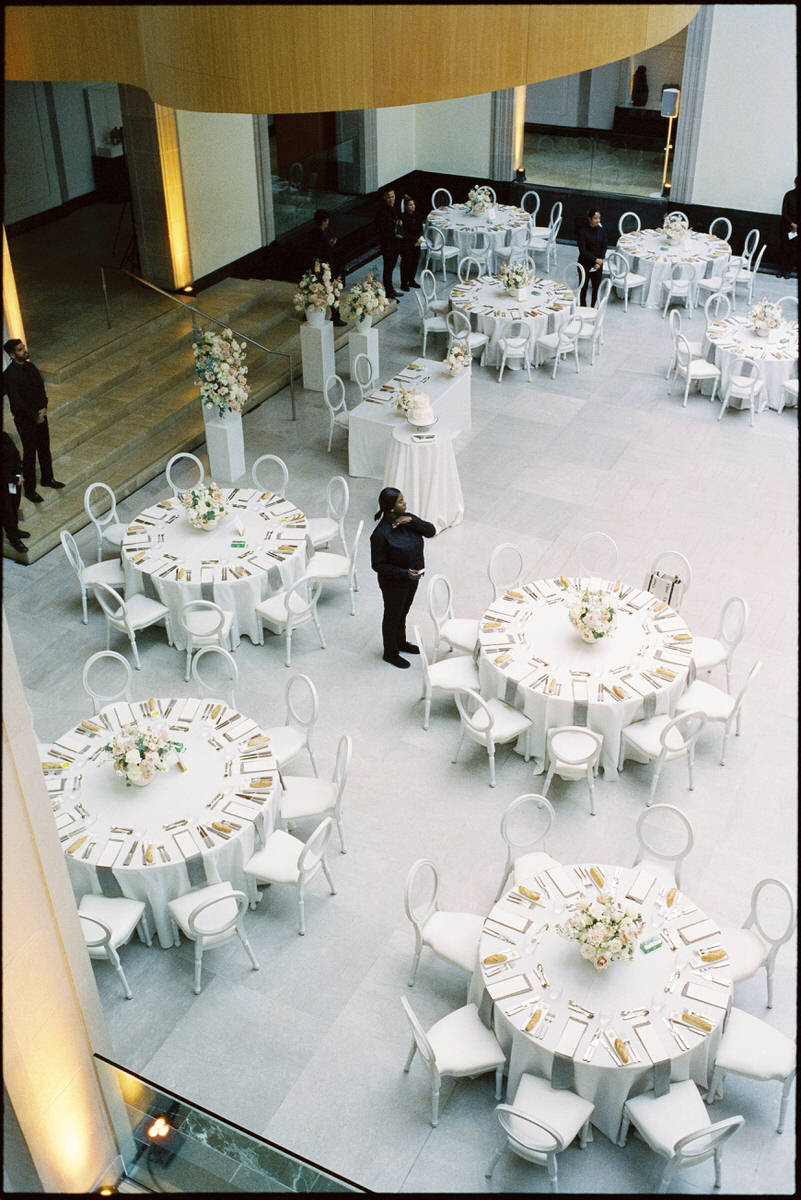 round rental tables being set up inside Walker Court at the AGO for a wedding reception