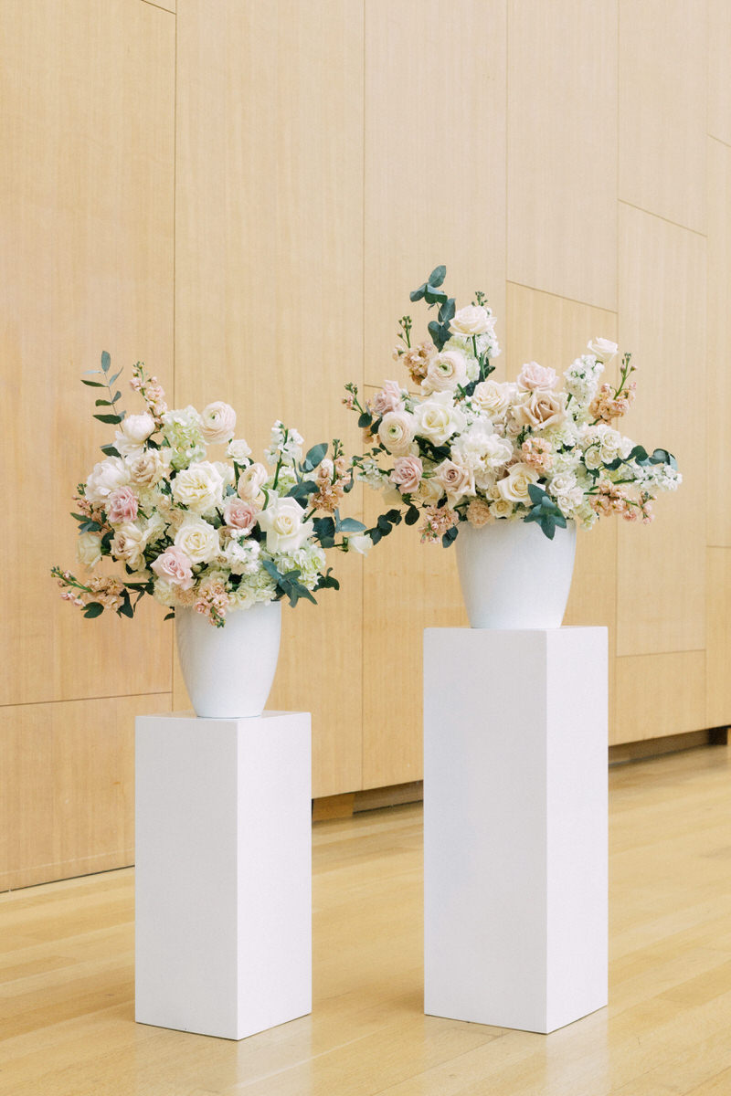 two large floral centrepieces on top of white marble plinths inside AGO Galleria Italia