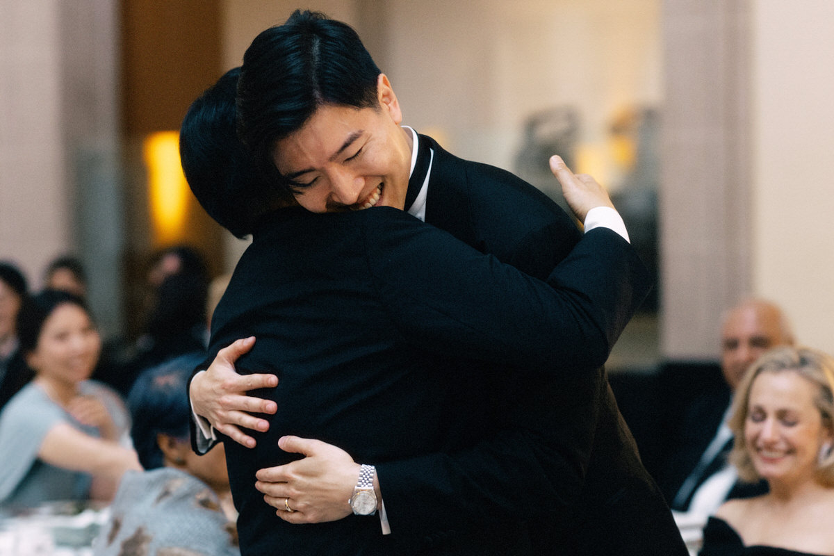 Asian son hugging father during a wedding reception in Toronto